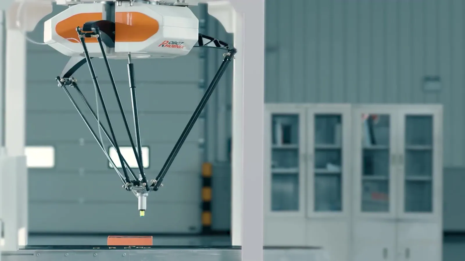 天井から吊られたパラレルリンク(Delta)ロボットが、コンベヤ上のワークに向かう様子